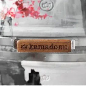 Nahaufnahme des „kamado B10" Holzgriffs vor einem mit Sakura-Motiven bemalten Korpus