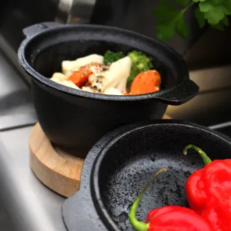 Two small, cast-iron pots containing assorted grilled vegetables
