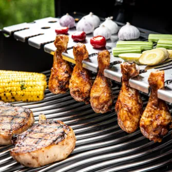 Close-up of a grill grate abundantly loaded with meat and vegetables