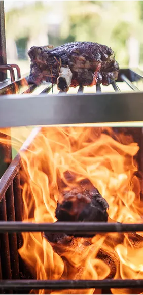 Nahaufnahme von Fleisch, das auf einem Grillrost über offenem Feuer gart.